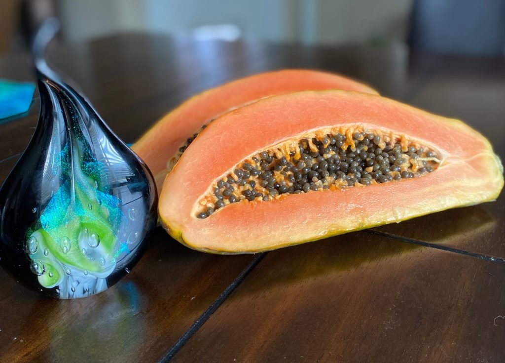 Cut Papaya showing little black, edible seeds inside. 