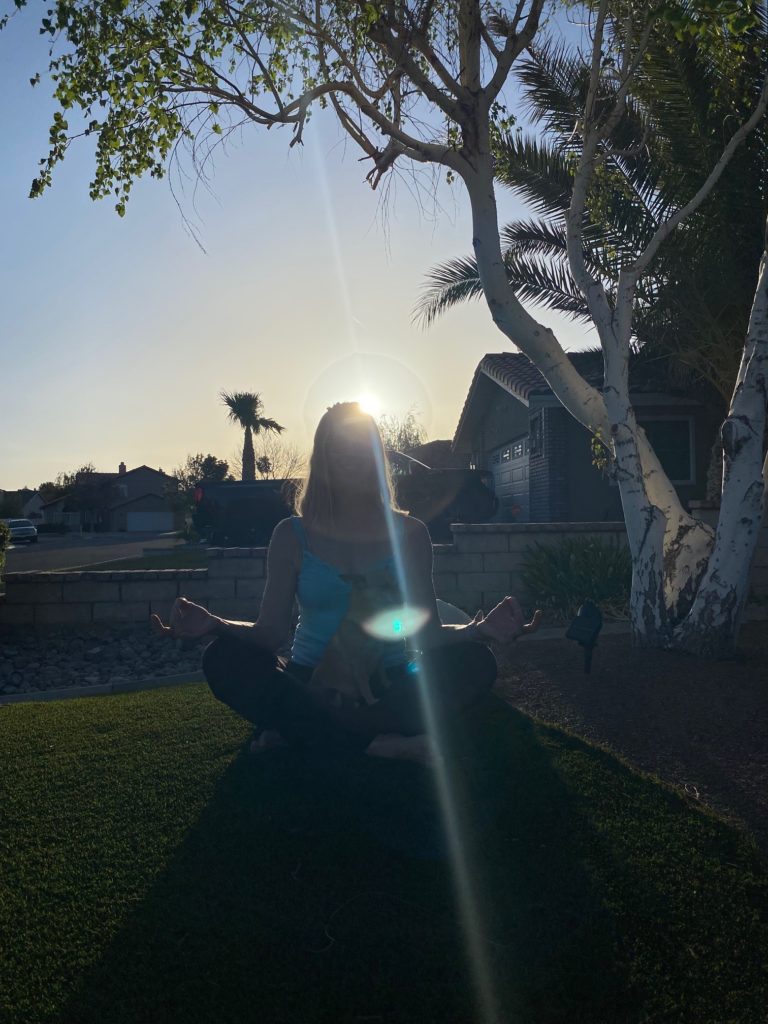 Girl sitting outdoors doing front yard yoga/meditation.  Defining self-care and its importance with front yard yoga/meditation. 